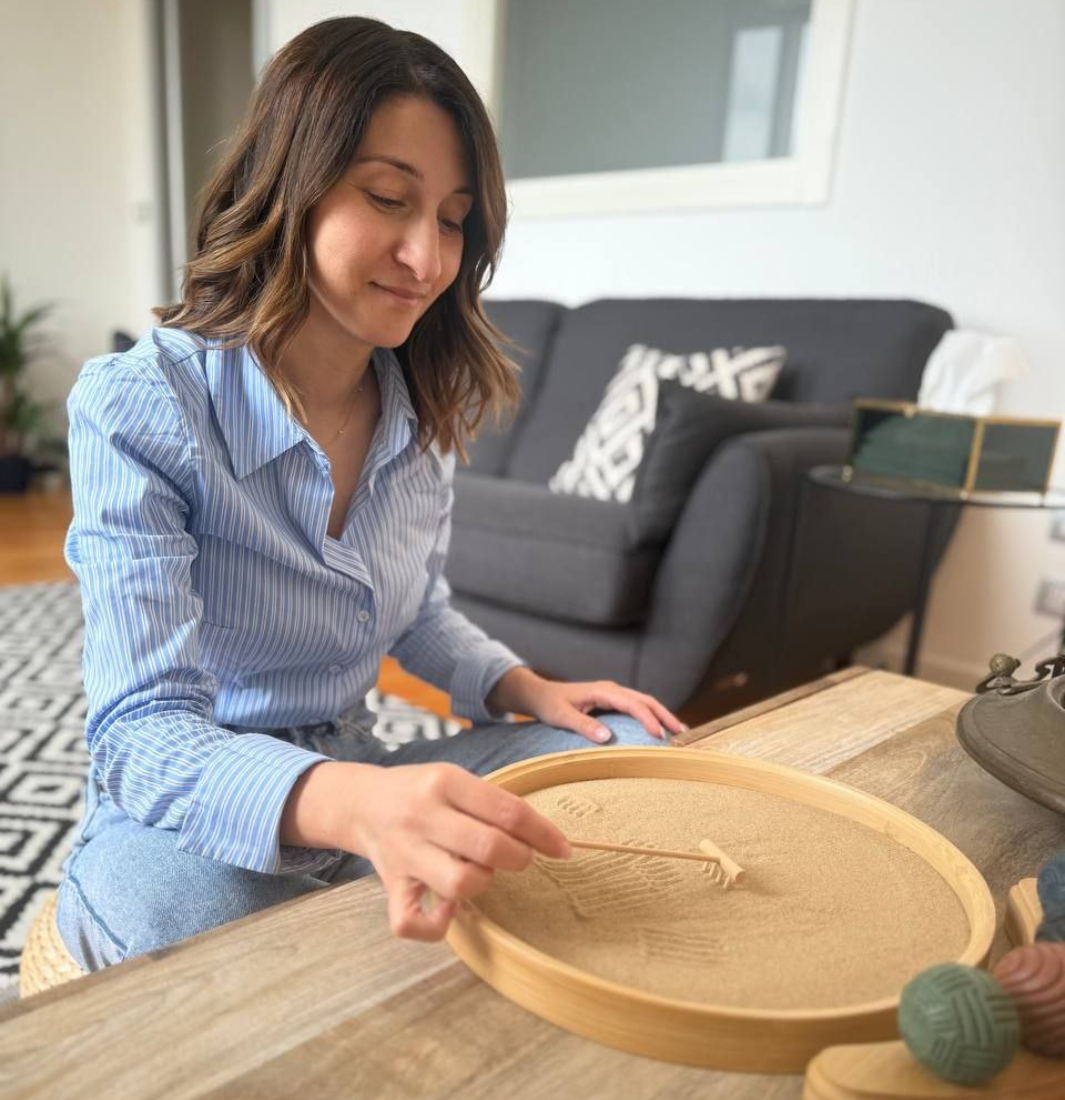 Donna psicologa a Sassari, seduta a un tavolo di legno, circondata da gomitoli di lana colorati.